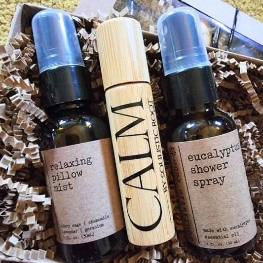 Three spa care and wellness bottles of essential oil products including 'relaxing pillow mist', 'eucalyptus shower spray', and a wooden roller bottle labeled 'CALM'.
