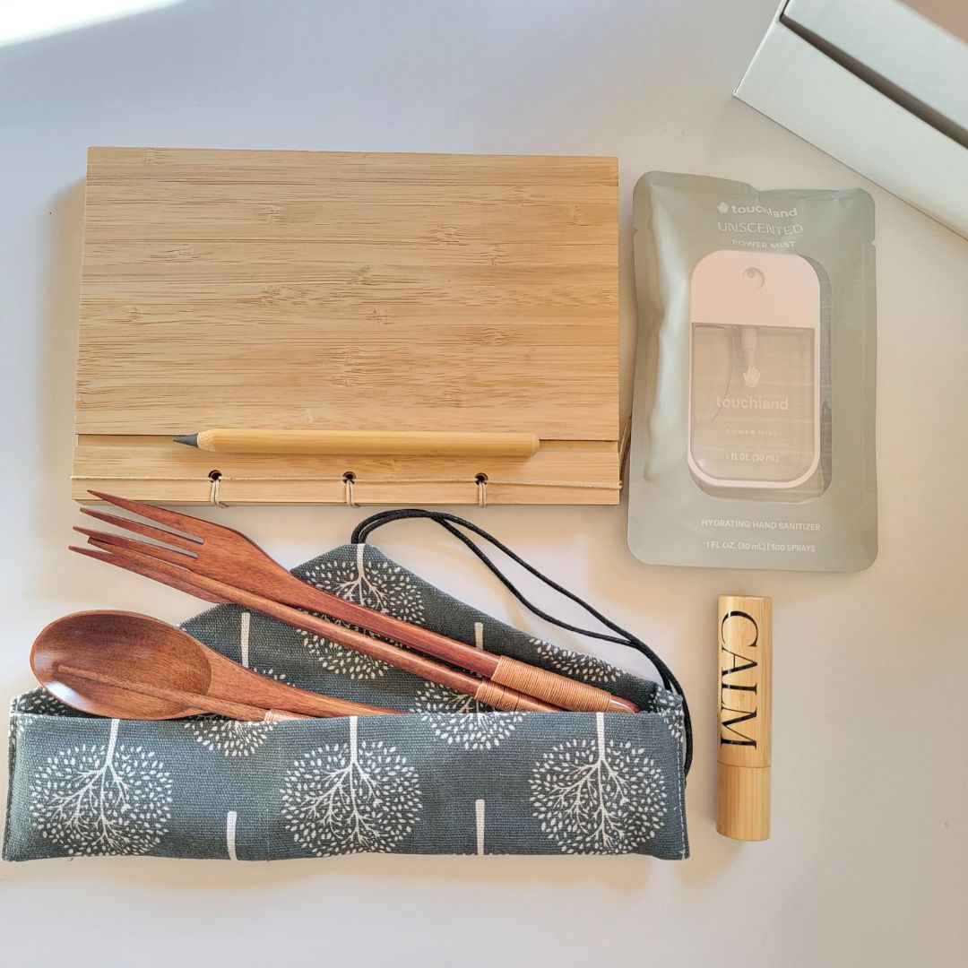 Sustainable corporate gift with eucalyptus hand sanitizer, bamboo notebook, never ending pencil, calm roll-on, and reusable cutlery wrap