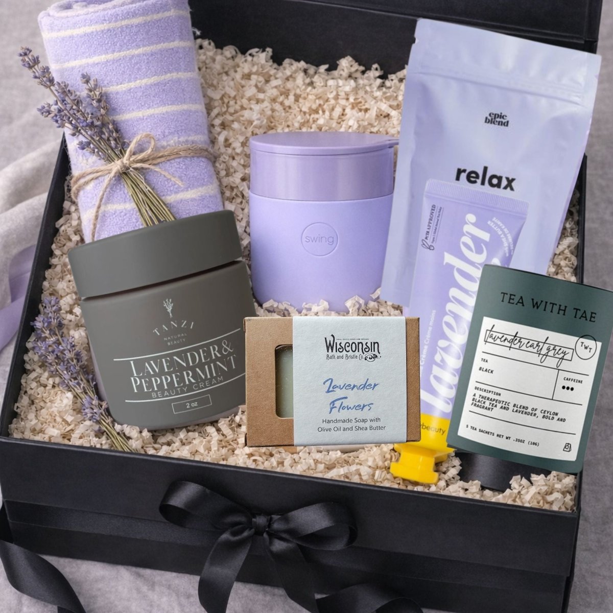 Lavender Spa Gift Box with tea, bath soak, hand cream, soap, face mask, blanket, and  ceramic tumbler. A beautiful Mother’s Day gift and relaxing spa gift for women.