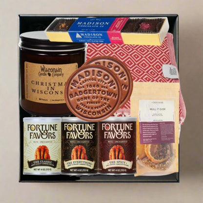 Wisconsin gift box featuring a red throw blanket, leather coasters, artisan pecans, chocolate bars, candle, and local seasoning in a black box