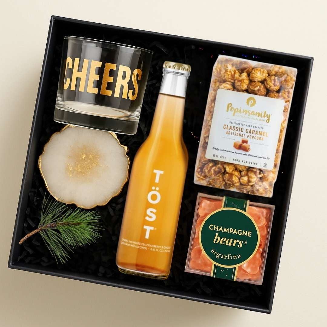 Executive Cheers Gift Box with a Cheers glass, TÖST sparkling tea, caramel popcorn, artisan coaster, and gourmet treats. A modern non-alcohol client appreciation gift.